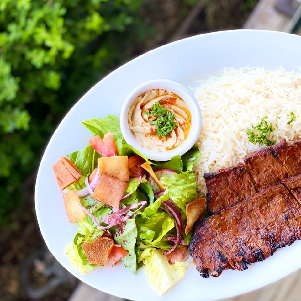 Tarme Mediterranean Grill's grilled meat platter with rice, hummus, and a fresh salad.