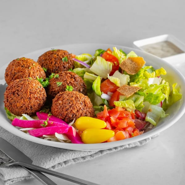Tarme Mediterranean Grill's falafel plate with fresh salad, pickled vegetables, and a side of sauce.