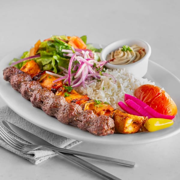 Tarme Mediterranean Grill's mixed grill plate with kebab, chicken, rice, salad, hummus, and pickles.